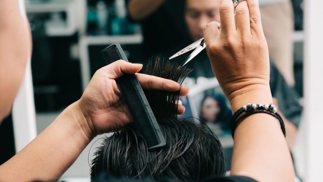estilista-masculino-irreconocible-que-corta-el-cabello-del-cliente-frente-al-espejo