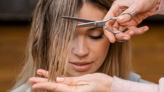 vista-frontal-de-la-mujer-cortandose-el-pelo-en-casa